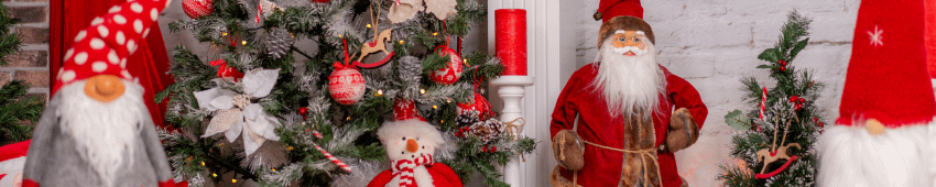 Inside of a home where a Christmas tree has standing plush figures next to it including a Santa Claus and a snowman.
