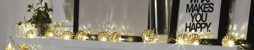 A set of golden ball Christmas lights laid out over a fireplace mantle.