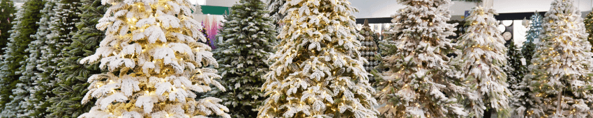 A selection of artificial Christmas trees on a display stand standing next to each other.